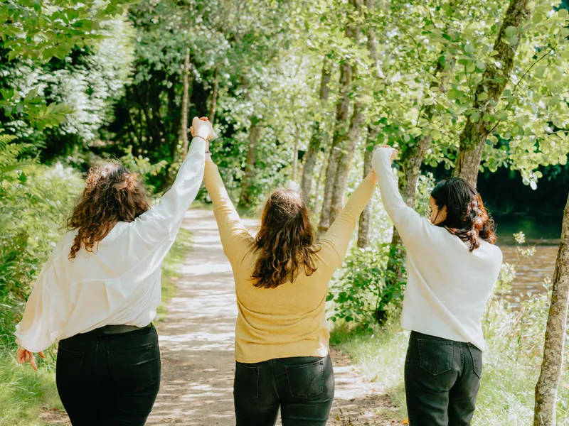 Three people raising their hands on a forest trail